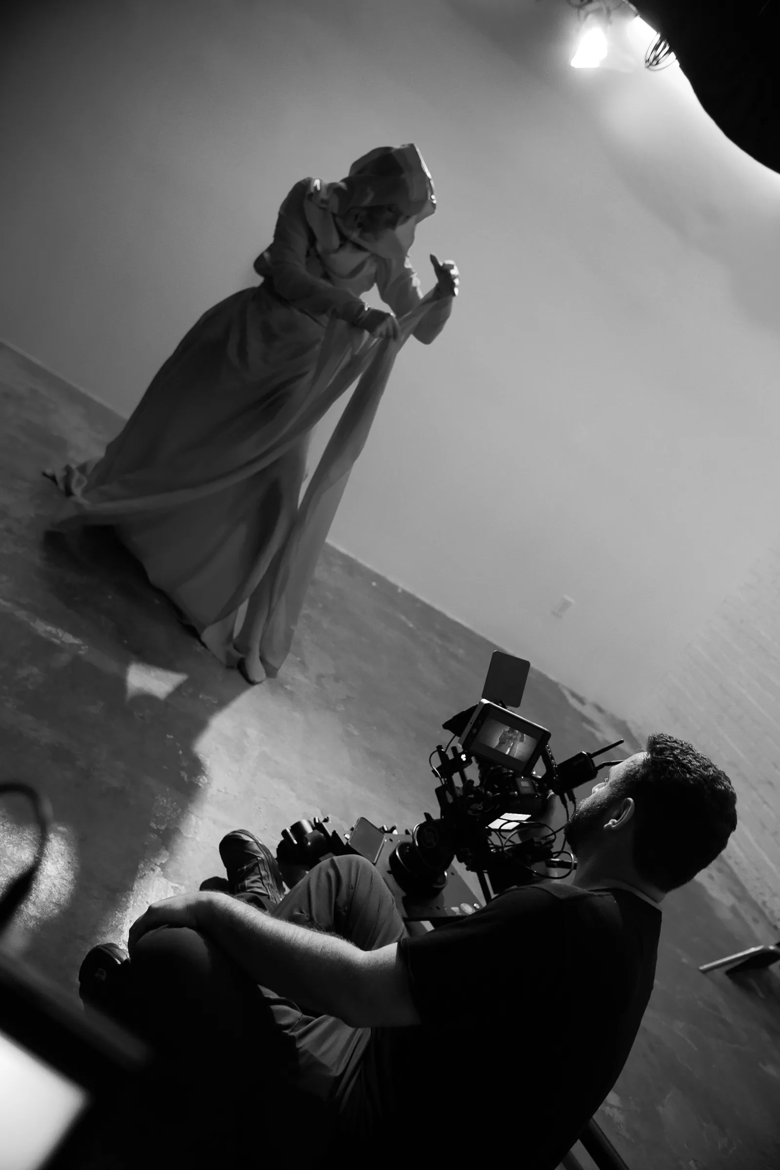 Black and white photo of a camera operator filming the entity from the floor